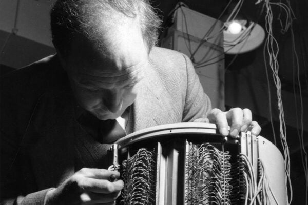 Christopher Strachey of the National Research Development Corporation demonstrates the memory drum of the Ferranti Mark 1, (also known as the Manchester Electronic Computer), which has 2,000 leads and functions in a similar way to the human brain, Moston, Manchester, February 1955.
