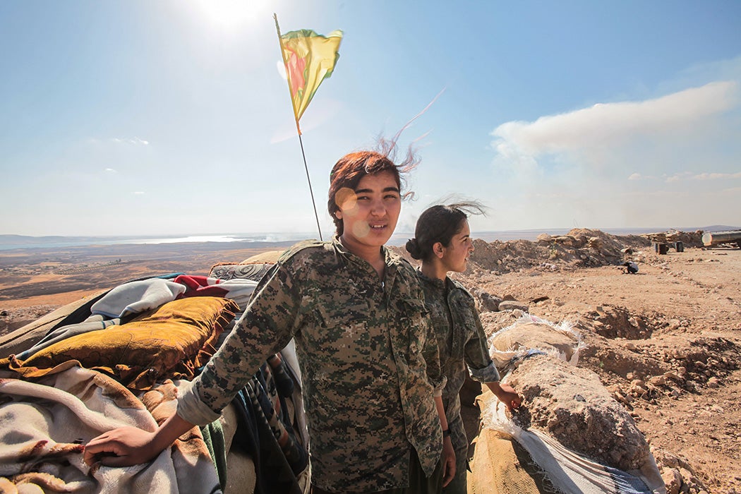 A Kurdish People's Protection Units, or YPG women fighters pose as they stand near a check point in the outskirts of the destroyed Syrian town of Kobane, also known as Ain al-Arab, Syria. June 20, 2015.