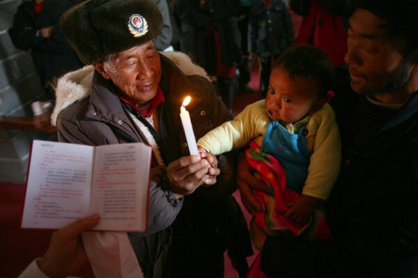 A priest holds a christening for a baby of Tibetan ethnic minority group attends a mass at a church of Cizhong Village on December 25, 2006 in Deqin County of Yunnan Province, China