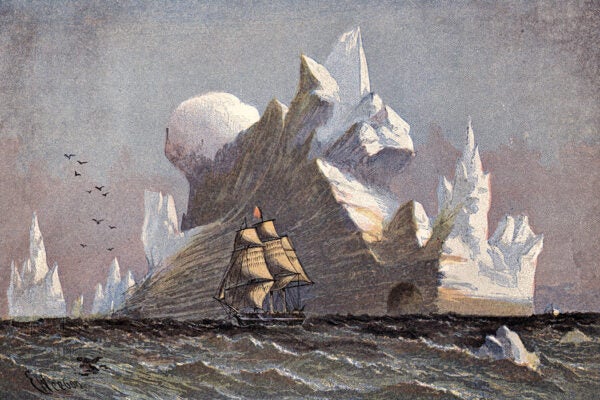 Icebergs towering over a sailing ship in Arctic waters.
