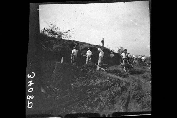Men in striped pants removing dirt or gravel from a ditch, 1911, Panama Canal Zone