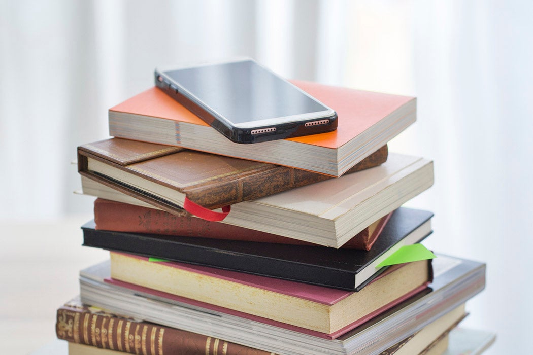 A high stack of books and a mobile phone