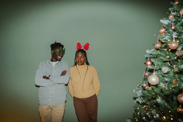 Photo of a playful couple in holiday accessories by the Christmas tree