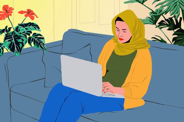 Young woman in hijab on a laptop on living room sofa