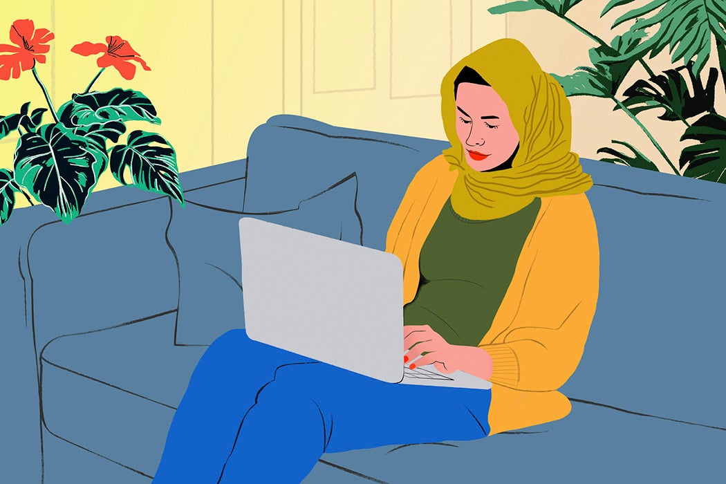 Young woman in hijab on a laptop on living room sofa