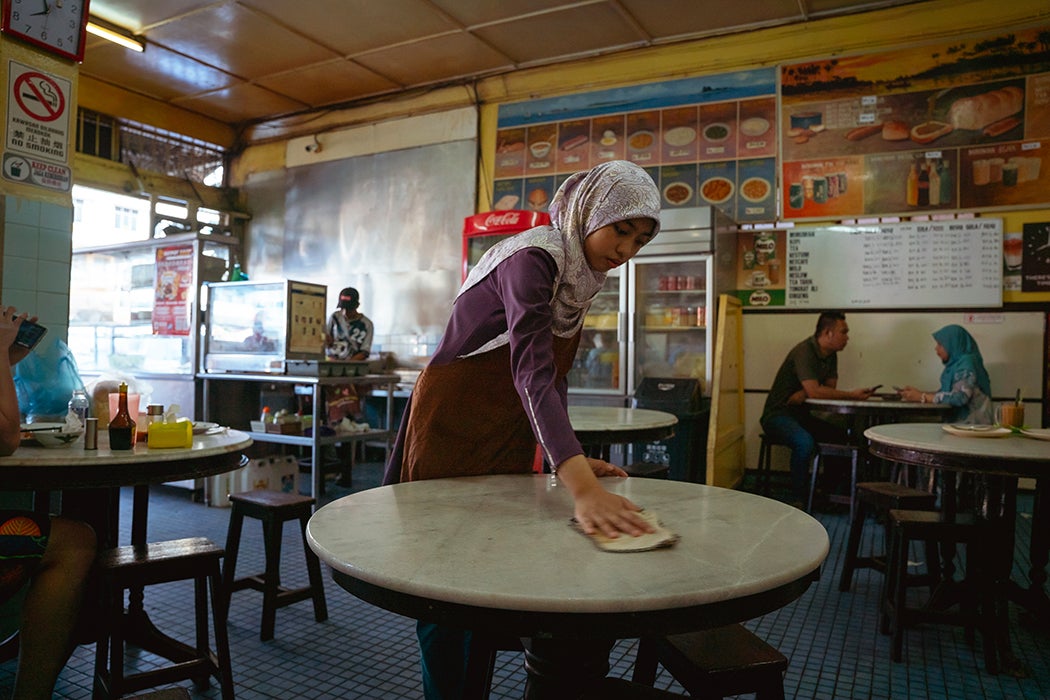 A stateless teenager wipes a table clean at a restaurant on May 23, 2024 in Semporna, Sabah, Malaysia. Many stateless teenagers and children find jobs to help support their families, but are often paid a fraction of what Malaysian nationals can earn.