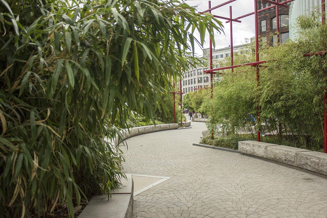 Chinatown Park View of serpentine path of the park. Red scaffold-like structures which support and frame the bamboo can be seen in the distance.