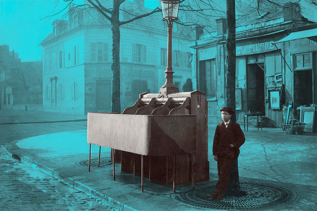 Cast iron and slate urinal with three stalls raised modesty screen, mounted with lamppost and lantern. Boy standing nearby beside lamppost, face blurred by movement. Avenue du Maine, Paris, France.
