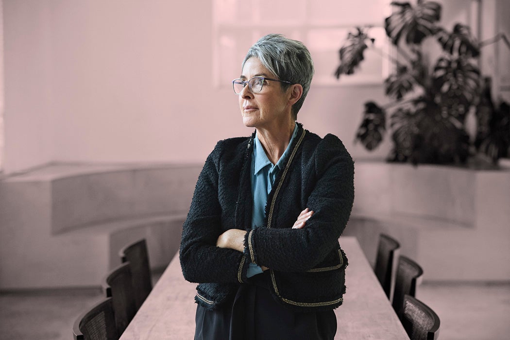 Contemplative short haired senior female entrepreneur looking away while standing with arms crossed in conference room